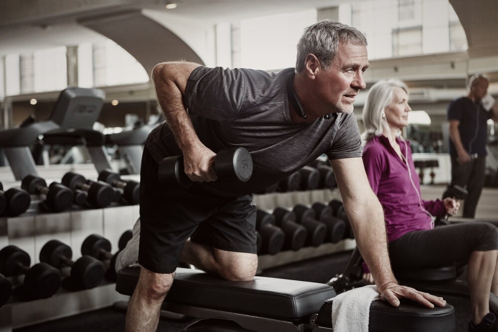 An adult doing a supported dumbbell row